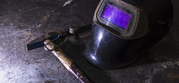 A closeup shot of a welding helmet near a hummer