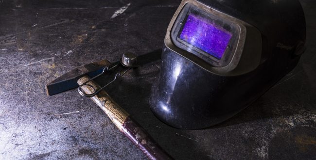 A closeup shot of a welding helmet near a hummer