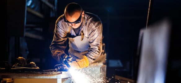 Worker cutting metal with plasma equipment on plant.