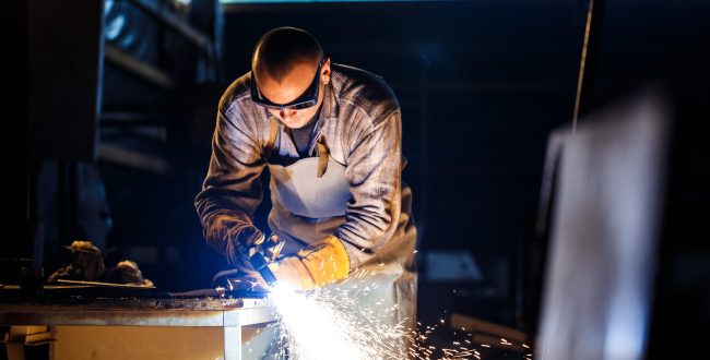 Worker cutting metal with plasma equipment on plant.