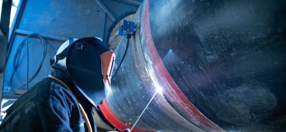 Professional welder welding pipe on a pipeline construction.