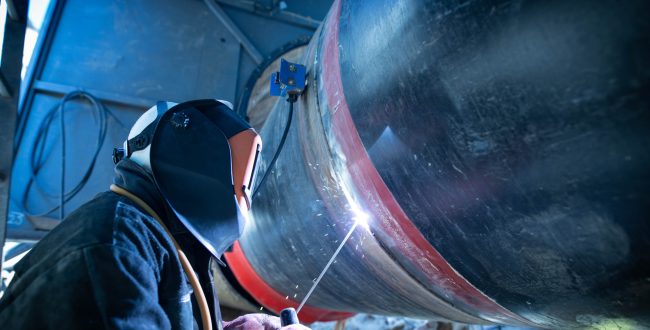 Professional welder welding pipe on a pipeline construction.